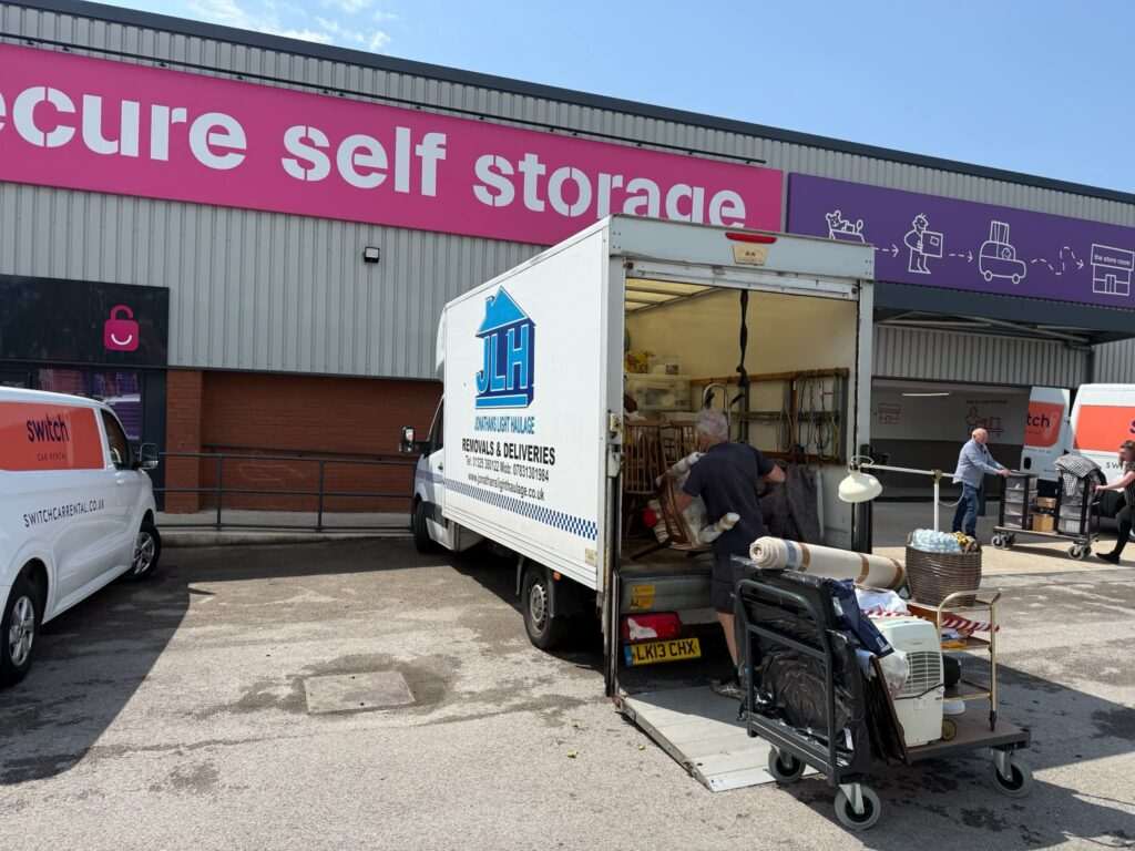 1 - Jonathan's Light Haulage Moving Truck and Open Delivery Van at a Self-storage Facility with a Bright Pink'self storage' sign on the building.