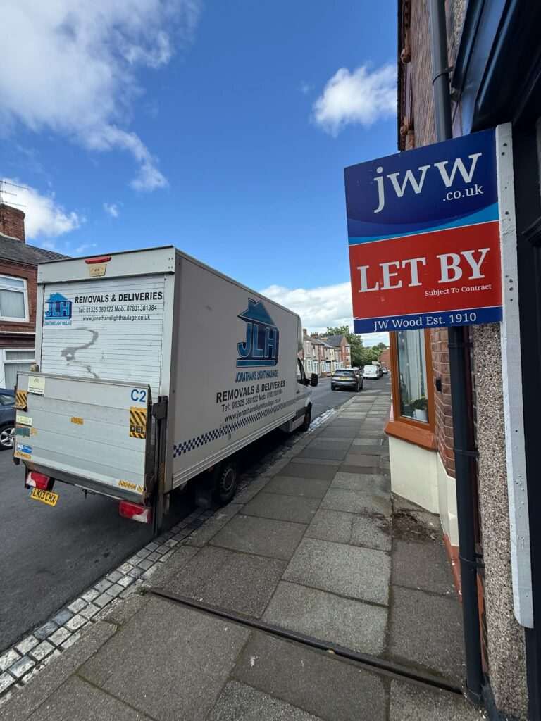 White Delivery Truck Parked on a Narrow Street with 'removals & Deliveries' Branding on the Side and a Blue/white 'jw Let By' Sign on a Building Beside the Sidewalk.